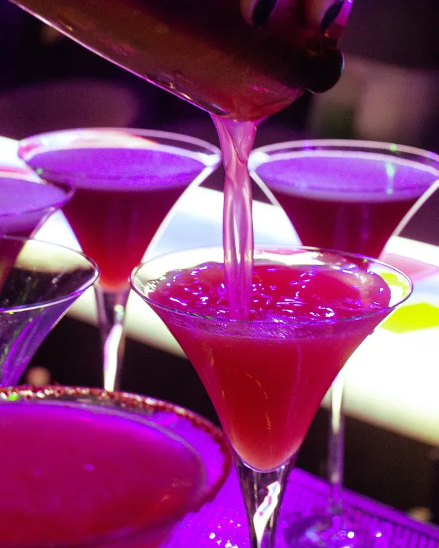 A vivid pink cocktail poured into a coupe at Lola’s Liquors