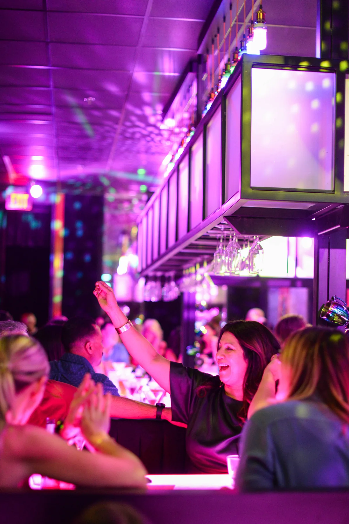 Friends gathered along the pink-lit bar at Lola’s Liquors