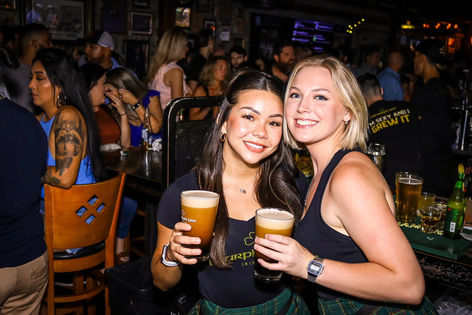 Two friends holding pints in the lively bar at Murphy’s Law