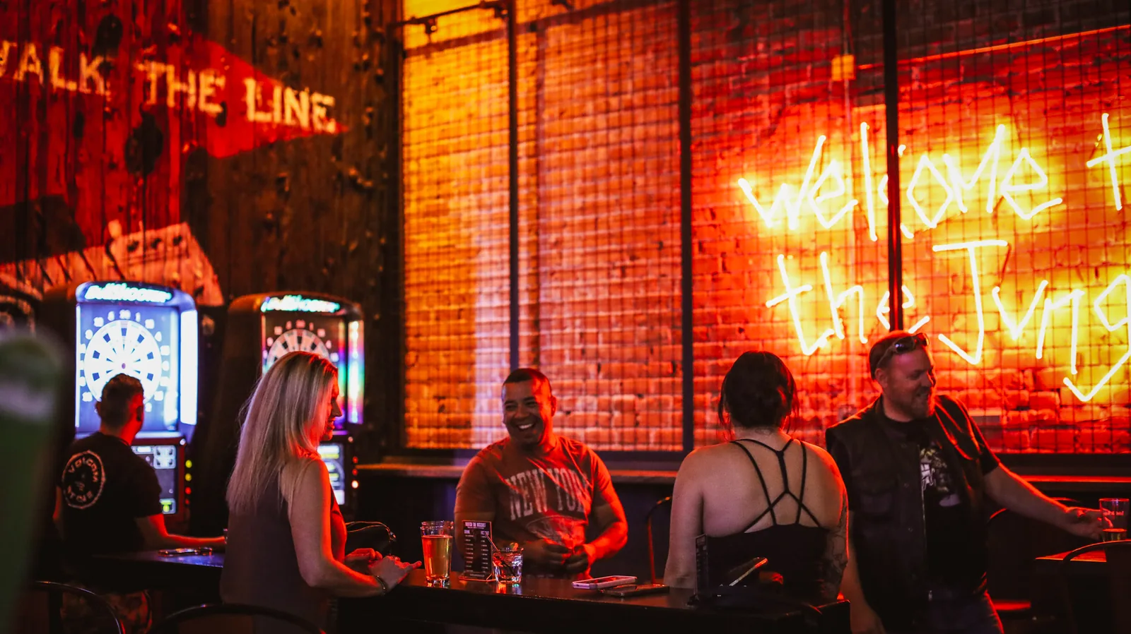 Friends beside the dartboards and red neon at Rebel & Rogue