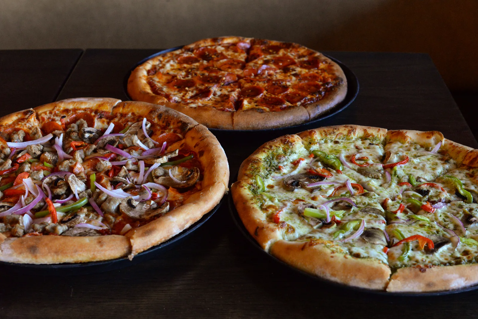 Three freshly baked pizzas on a table at Rebel & Rogue